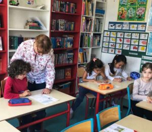 Petite fille en maternelle arrosant des plantes lors d’un cours en anglais