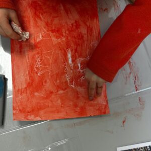 Enfant appliquant de la peinture rouge sur une feuille pendant un atelier créatif à Fontainebleau