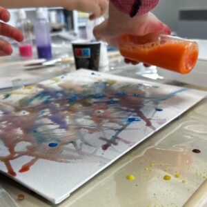 Enfant versant de la peinture sur une toile pendant un atelier créatif au CAB à Fontainebleau