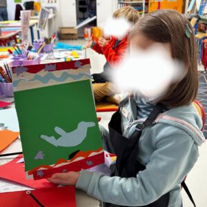 Enfant présentant une création en papier réalisée pendant un atelier d’arts plastiques à Fontainebleau